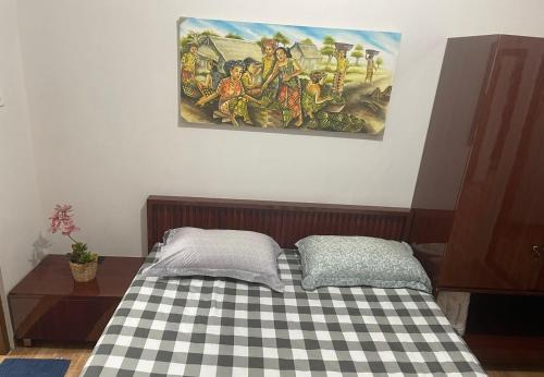 a bed in a room with a painting on the wall at Homestay Omah Embun in Godean