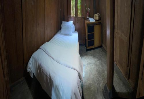 a bedroom with a bed with white sheets and a window at Homestay Omah Embun in Godean