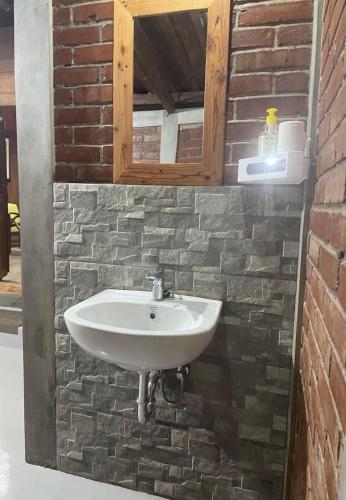 a bathroom with a sink and a brick wall at Homestay Omah Embun in Godean