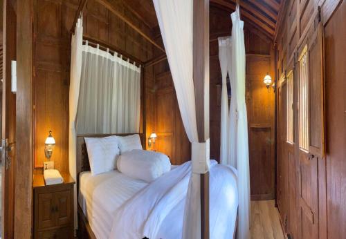 a bedroom with a bed with white sheets at Homestay Omah Embun in Godean