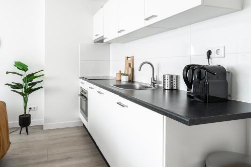 eine weiße Küche mit einer schwarzen Arbeitsplatte und einem Waschbecken in der Unterkunft 6p newly renovated home with unique roof-terrace in Strijp