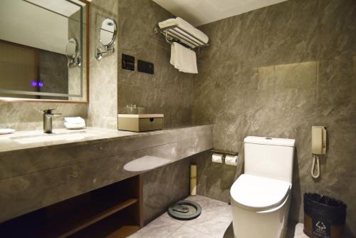 a bathroom with a toilet and a sink and a mirror at Guangdong Hotel-Free Shuttle & Registration Counter Service during Canton Fair in Guangzhou
