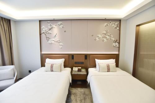 two beds in a room with flowers on the wall at Guangdong Hotel-Free Shuttle & Registration Counter Service during Canton Fair in Guangzhou