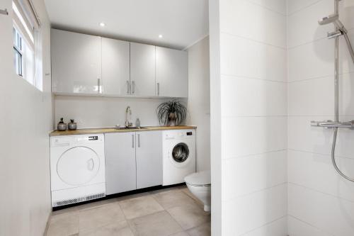 a white bathroom with a washing machine and a toilet at Holiday Home With A Wilderness Bath, Only 100 Meters From The Lovely Beach in Marielyst