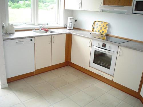 une cuisine avec des armoires blanches et des appareils électroménagers blancs dans l'établissement Nice Home In Rudkøbing With 3 Bedrooms, Sauna And Wifi, à Spodsbjerg