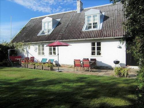 a white house with a table and chairs and an umbrella at Amazing Home In Höganäs With 2 Bedrooms And Wifi in Höganäs
