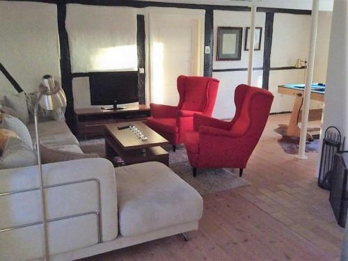 a living room with red chairs and a tv at Amazing Home In Höganäs With 2 Bedrooms And Wifi in Höganäs