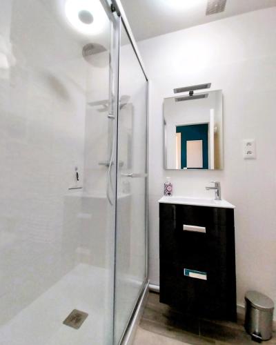 a bathroom with a glass shower and a sink at Charmant appartement bord de mer in Dinard