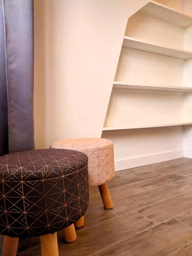 a chair and a stool in front of shelves at Charmant appartement bord de mer in Dinard