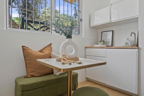 a kitchen with a table and a chair with a vase on it at Belles Bondi Beach Apartments - 1 and 2 Bedroom Stays - 500m to beach in Sydney