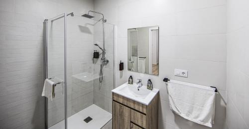 a white bathroom with a sink and a shower at Apartamentos Luxury en San Juan in Badajoz