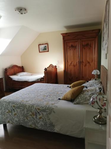 - une chambre avec un grand lit et une armoire en bois dans l'établissement Chambre d'hôtes Le Pot au Lait, à Villaines-la-Juhel
