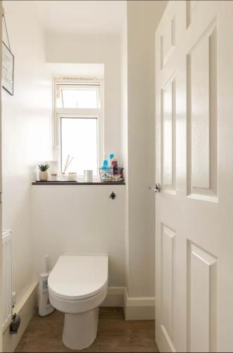 a white bathroom with a toilet and a window at Charming Double Room Near Richmond Park Kingston Gate in Kingston upon Thames