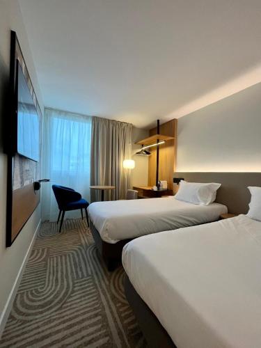 a hotel room with two beds and a desk at Golden Tulip Villepinte Roissy - Parc des Expositions in Roissy-en-France