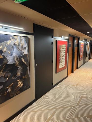 a hallway with paintings on the walls of a building at Golden Tulip Villepinte Roissy - Parc des Expositions in Roissy-en-France