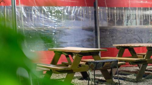 two picnic tables and a grill in front of a tent at Anmyeondo paradise pension in Taean