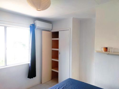 a bedroom with a window and a bed with blue sheets at Colibri in Noumea