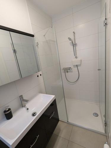 a white bathroom with a shower and a sink at Ferienwohnung "EDDI" in Hohnstein