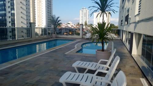 莫日-达斯克鲁济斯Loft, seu espaço com conforto的一座带两把椅子的游泳池,一座棕榈树