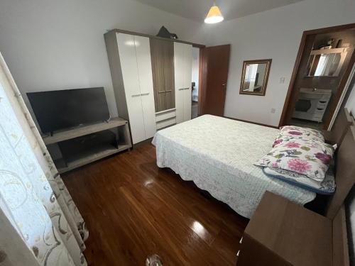 Un dormitorio con una cama y un televisor de pantalla plana. en Casa de praia com piscina, en Río Grande