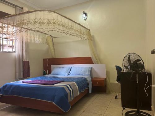 a bedroom with a canopy bed and a fan at Luxury 1 BER Apartment Bukoto in Kampala