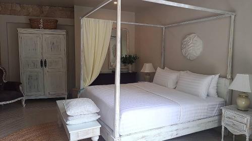 a bedroom with a white bed with a four post canopy at O - HO Boutique Home in Baan Tai