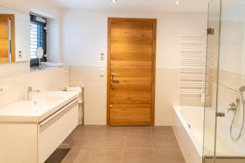 a bathroom with a tub and a sink and a shower at Appartements Kirchenwirt in Kirchberg in Tirol