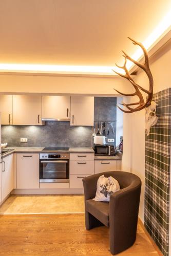 a kitchen with a chair and a deer head on the wall at Appartements Kirchenwirt in Kirchberg in Tirol