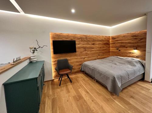 a bedroom with a bed and a television on a wall at Alpenblick - klein, aber fein in Schladming