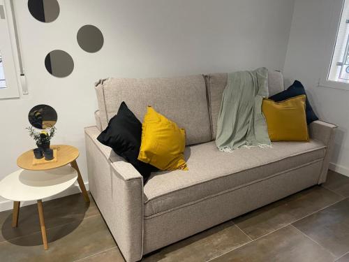 a gray couch with yellow pillows and a table at La Pitxotxa - Apartamento in Novelda