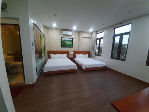 two beds in a room with two windows at Luxury Airport Hotel & Travel in Noi Bai