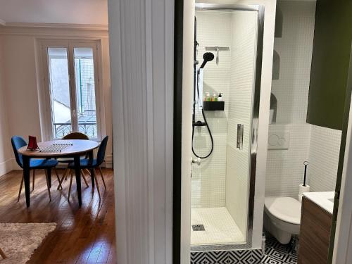 La salle de bains est pourvue d'une douche, d'une table et de toilettes. dans l'établissement Appartement cosy à Montmartre, à Paris