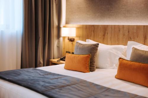 a hotel room with a bed with orange and white pillows at Valtur Cervinia Cristallo Ski Resort in Breuil-Cervinia