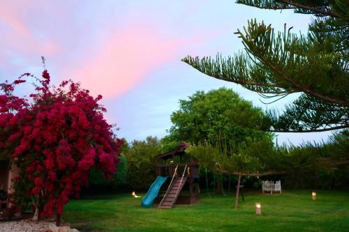 a playground with a slide and a tree with pink flowers at Es Molí d'en Mig, jacuzzi, piscina y barbacoa in Consell