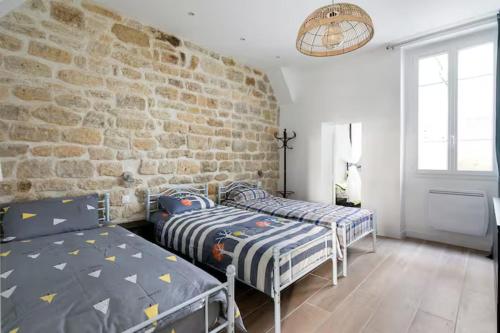 une chambre avec deux lits et un mur de briques dans l'établissement Mon Logis, à Paris