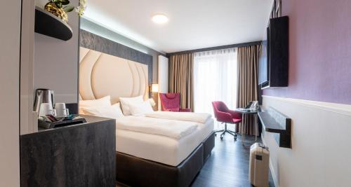 a hotel room with a bed and a desk at PLAZA Premium Heidelberg in Heidelberg