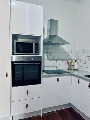 a kitchen with white cabinets and a microwave at Charming home in Central Dubbo in Dubbo