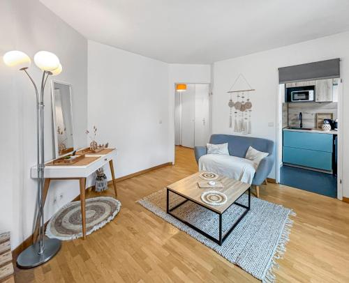 un salon avec un canapé bleu et une table dans l'établissement Studio cosy avec Smart TV & Wi-Fi, au Plessis-Robinson