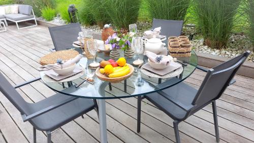 a glass table with a bowl of fruit on a patio at Les Wespellières 1897 - En vis à vis de Pairi Daiza in Brugelette