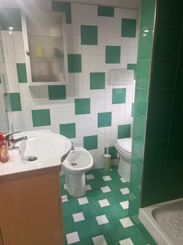 a green and white bathroom with a sink and toilet at La casetta del Pastore in Sulmona
