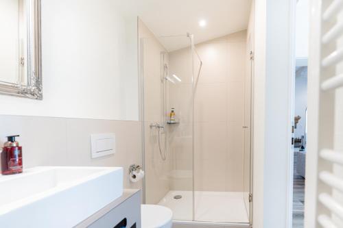a white bathroom with a shower and a toilet at Amazing Modern & Great equipped Jacuzzi Apartment in Kandersteg