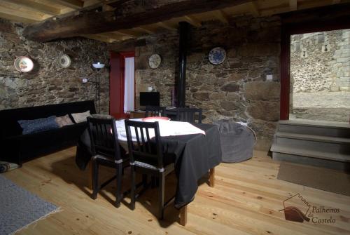 una mesa y sillas en una habitación con una pared de piedra en Palheiro do Castelo - Pátio, en Sabugal