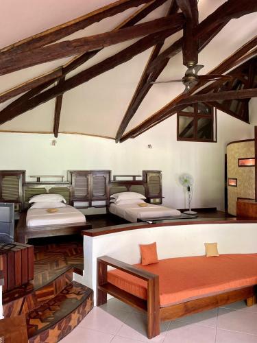 a room with three beds and a couch in it at Ravintsara Wellness Hotel in Ambaro