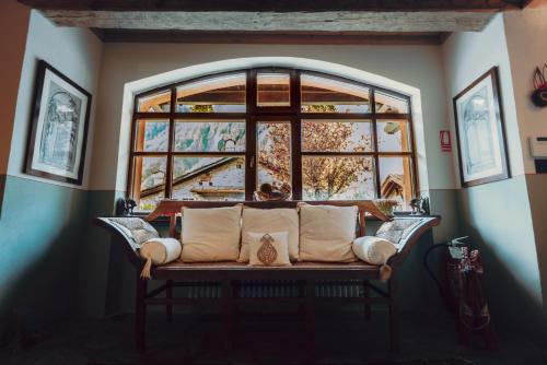 a couch in a room with a large window at Locanda La Brenva - Estella Hotel Collection & Experience in Courmayeur