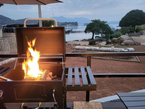 a fire pit with a bench next to a grill at Namhae Sea Sky Caraville Ocean View in Namhae
