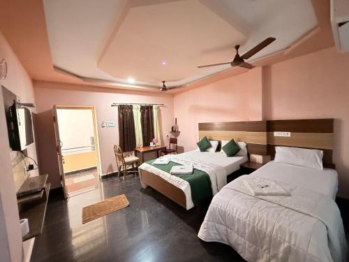 a hotel room with two beds and a television at Sri Murugan Beach Paradise Hotel in Mahabalipuram