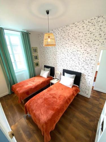 a bedroom with two beds and a chandelier at O jardin sakura in Les Portes du Coglais