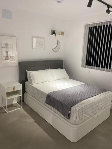 a white bedroom with a bed and a window at Smart Residencial in Villanueva de la Cañada