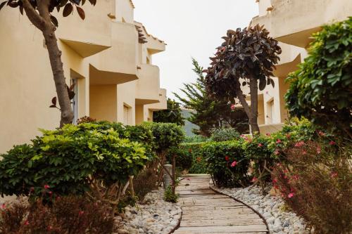 a walkway in front of a building with flowering plants at Aparthotel Villas La Manga in La Manga del Mar Menor