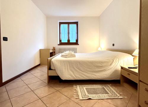a bedroom with a white bed and a window at Etrusca Polsa in Brentonico